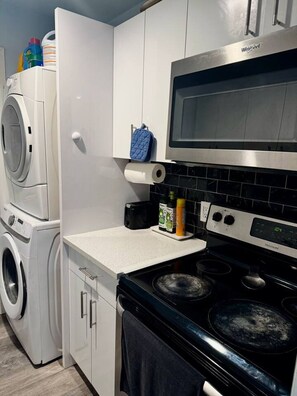A compact kitchen with a washing machine, a microwave, and a stove.