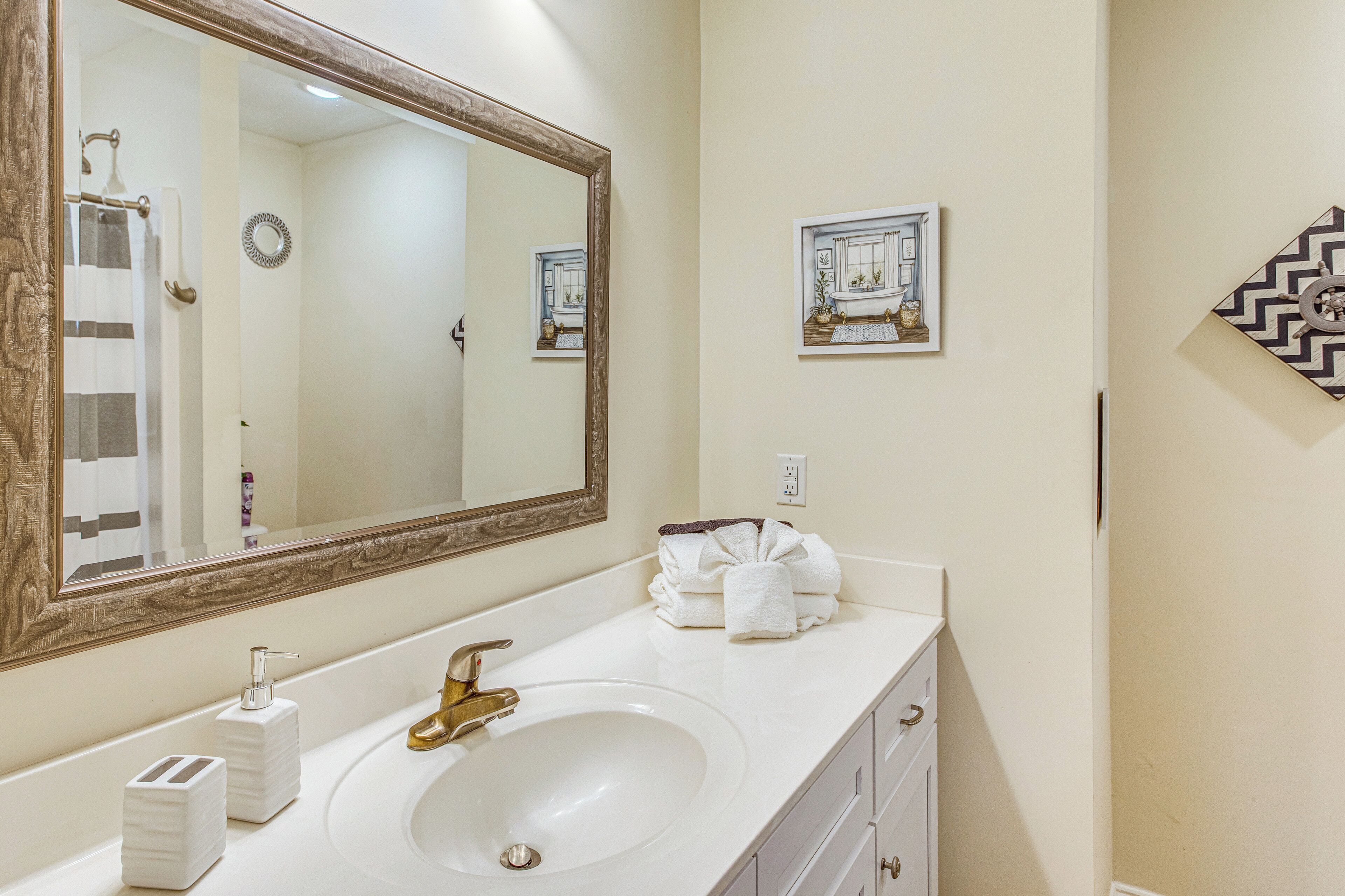 Une salle de bain avec un grand miroir, un lavabo, un porte-serviettes et un tableau accroché au mur.