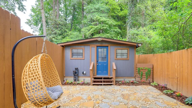 A house with a blue door, a hanging chair, and a stone pathway leading to the entrance.