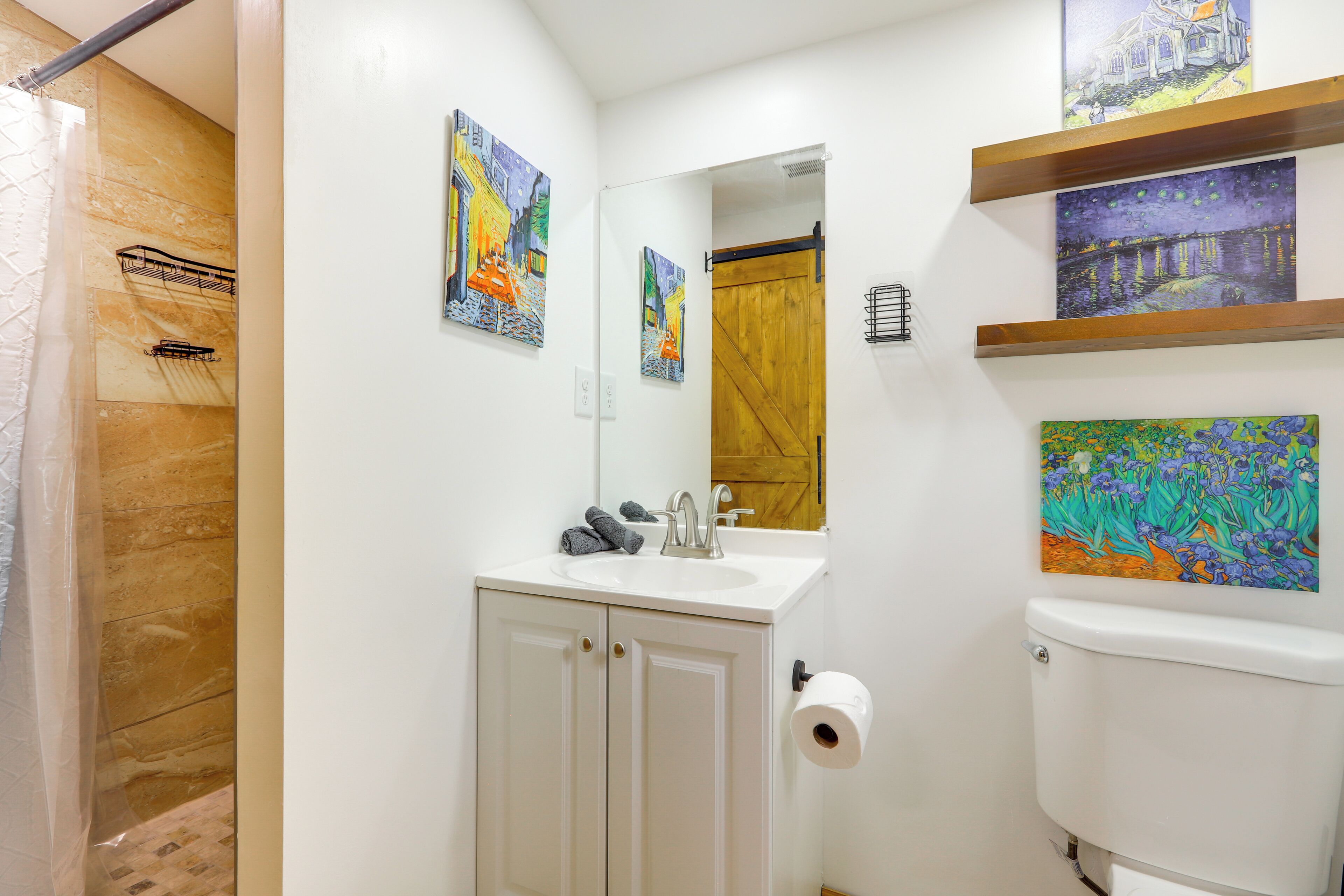 A bathroom with a sink, mirror, toilet, and shower.