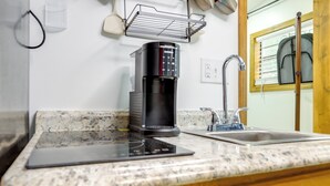 A kitchen with a coffee maker, a sink, and a window with blinds.