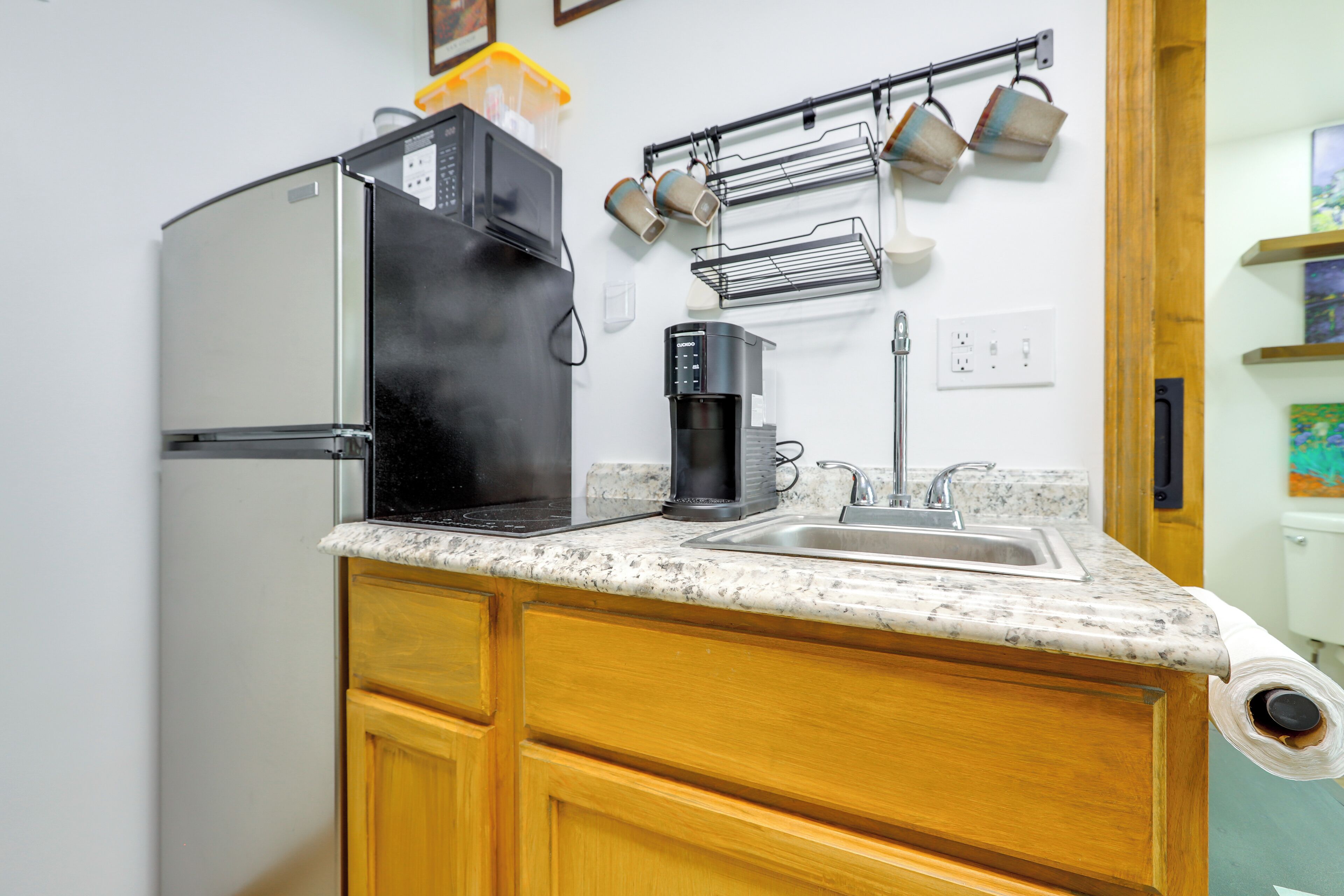 A kitchen with a refrigerator, coffee maker, and a sink.