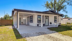 A modern single-story house with a covered porch, a fenced yard, and a large tree. - Work & Play in Palmetto! Pet-friendly Home w/ Yard (Palmetto)