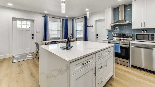 A modern kitchen with white cabinetry, stainless steel appliances, and pendant lighting. - Work & Play in Palmetto! Pet-friendly Home w/ Yard (Palmetto)