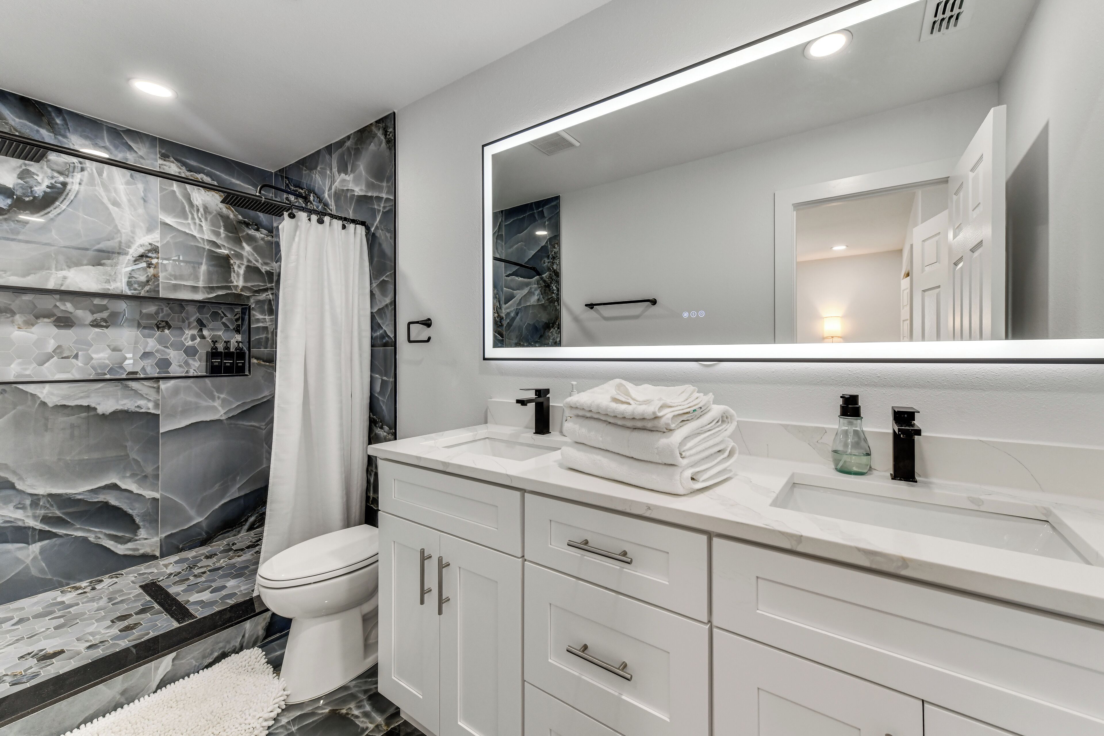 A modern bathroom with a shower, toilet, and vanity with a mirror.