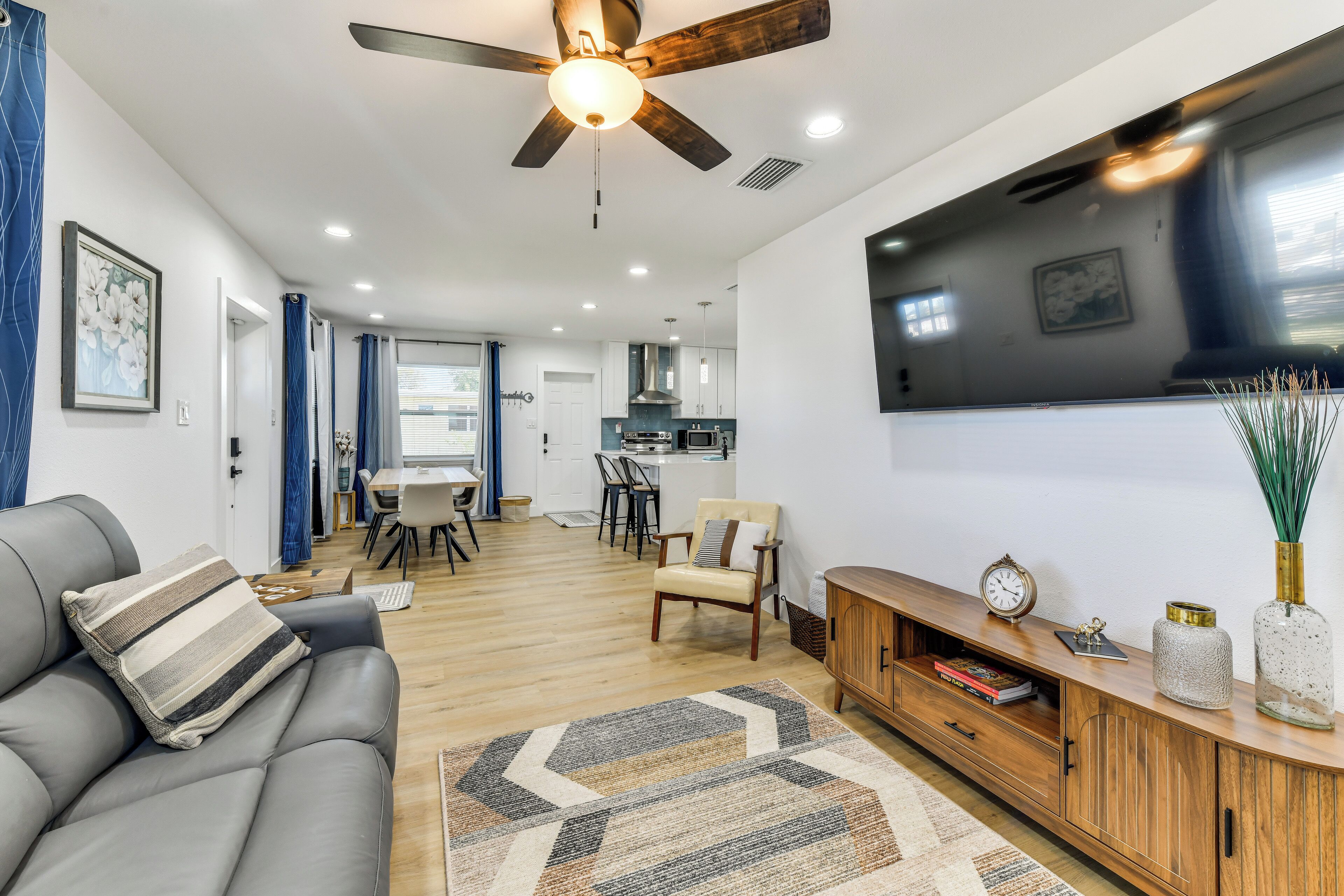 Un salon moderne avec un canapé, une console en bois, un téléviseur et un ventilateur de plafond.