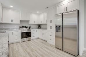 A modern kitchen with white cabinets, stainless steel appliances, and a granite countertop.