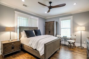 A bedroom with a bed, nightstand, chair, desk, and wardrobe.