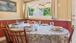 A dining room with a table set for four, chairs, a window with curtains, and a framed picture on the wall. - Walk to Parks & Dining: Bonner Springs Home (Bonner Springs)