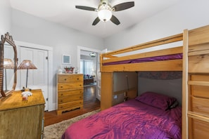 Une chambre à coucher avec un lit superposé, une commode en bois et un ventilateur de plafond.