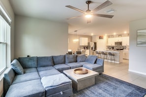 A modern living room with a sectional sofa, a coffee table, and a ceiling fan.