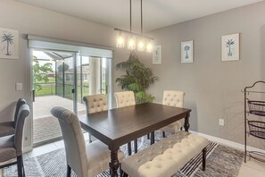 A dining area with a dark wooden table, cushioned chairs, a bench, and a potted plant.