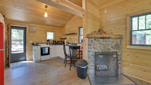 A wooden cabin interior with a kitchen, dining area, and stone fireplace. - Nature Lover's Getaway: Studio by Pigeon River (Vanderbilt)
