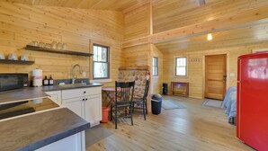 A wooden cabin interior with a kitchen, dining area, and a red refrigerator. - Nature Lover's Getaway: Studio by Pigeon River (Vanderbilt)