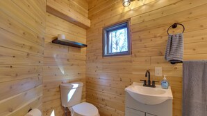 A wooden cabin bathroom with a toilet, sink, and window. - Nature Lover's Getaway: Studio by Pigeon River (Vanderbilt)