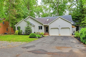 A two-story house with a garage, surrounded by trees and a well-maintained lawn.