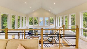 Ein geräumiges Zimmer mit großem Fenster, einer Treppe und Blick auf ein Gewässer.
