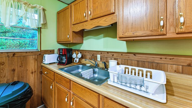 A kitchen with wooden cabinets, a sink, a toaster, and a coffee maker. - Bring Your Pets! Walkable Retreat in Manchester (Manchester)