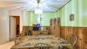 A dining room with a floral tablecloth, wooden chairs, a chandelier, and a wooden cabinet. - Bring Your Pets! Walkable Retreat in Manchester (Manchester)