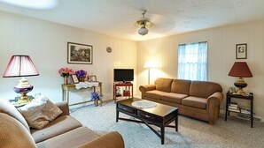 A living room with a sofa, a coffee table, a television, and a lamp. - Bring Your Pets! Walkable Retreat in Manchester (Manchester)