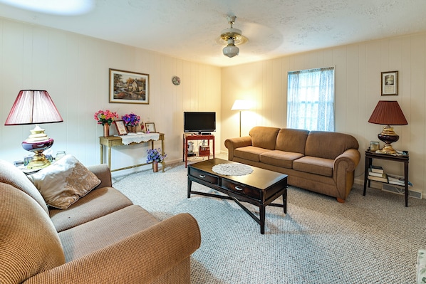 A living room with a sofa, a coffee table, a television, and a lamp.