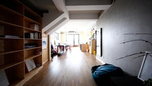 Un couloir avec une bibliothèque en bois, un fauteuil en forme de poire bleu et un tableau encadré accroché au mur.