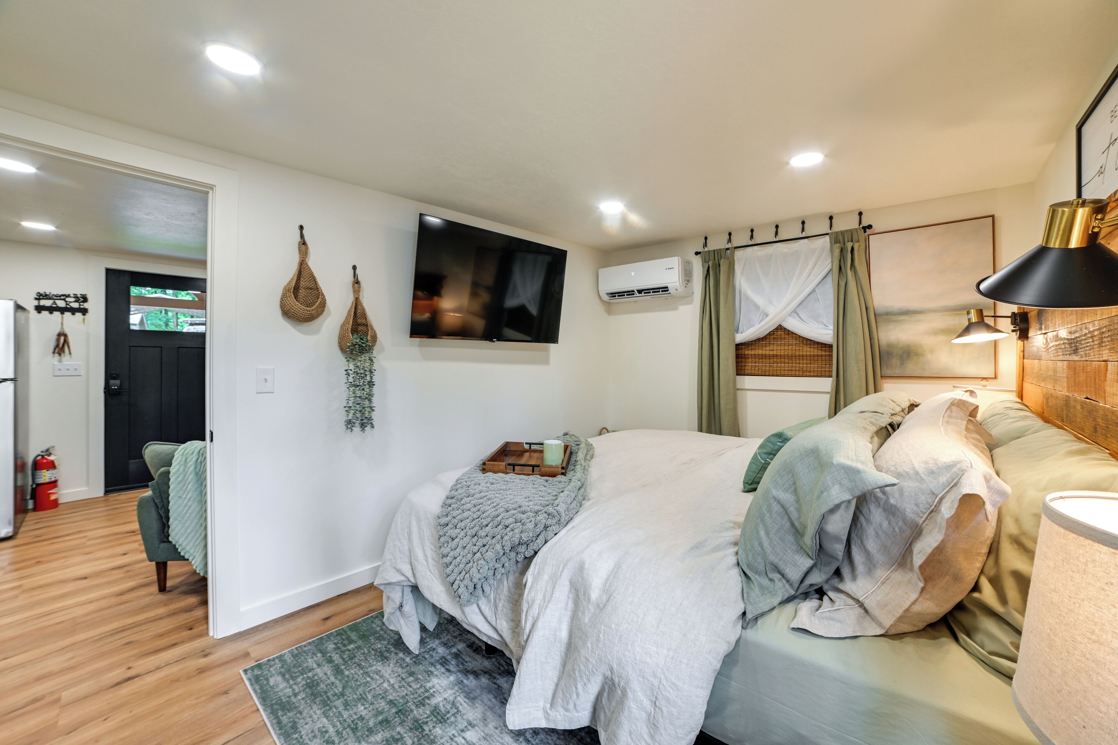 Une chambre à coucher avec un lit, une télévision, un climatiseur et une lampe.