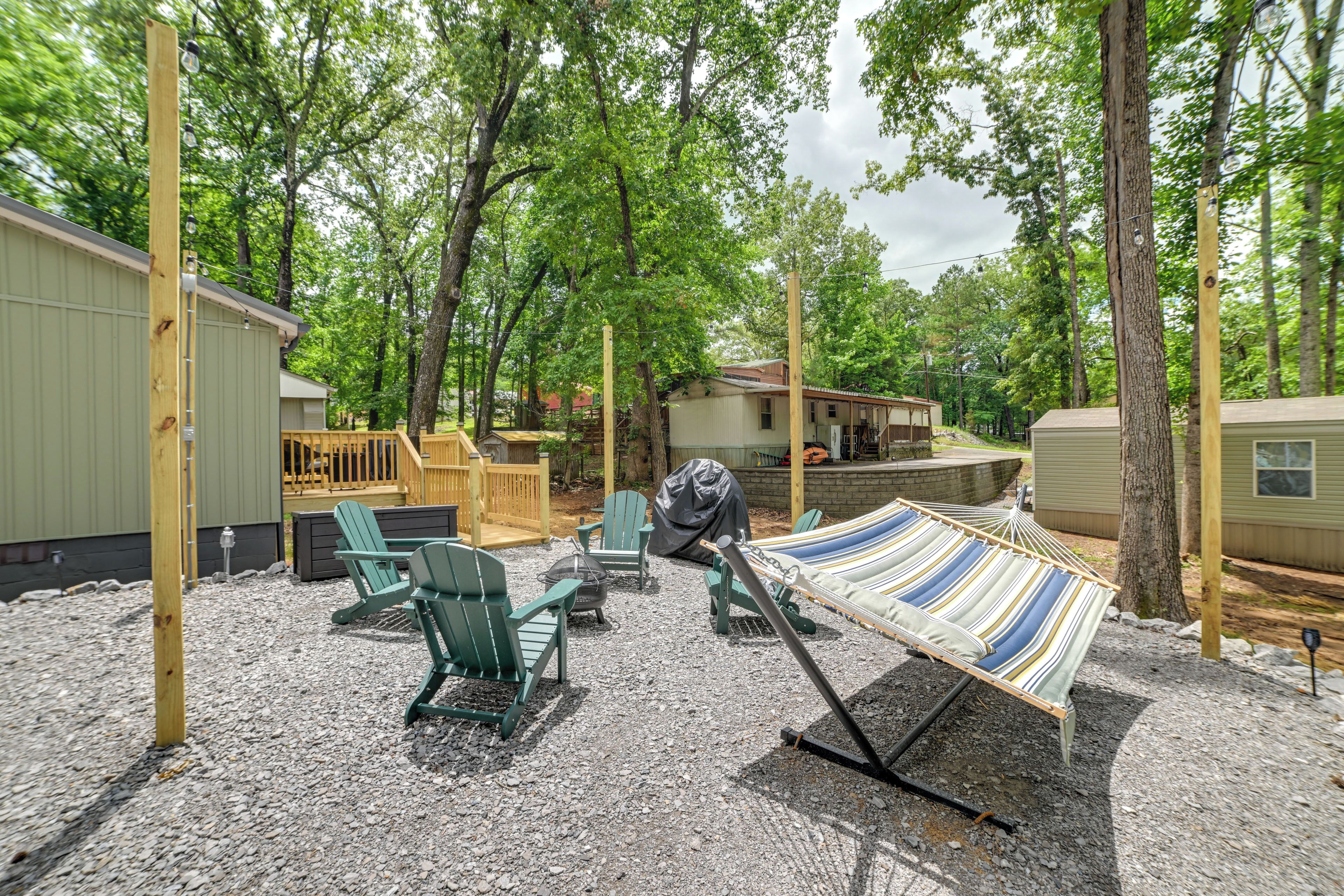 A campground with green Adirondack chairs, a hammock, and a covered picnic table.