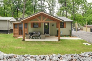 A small cabin with a porch, a grill, and a wreath on the door. - Hot Tub, Deck! Tiny Home Retreat By Kentucky Lake (Springville)