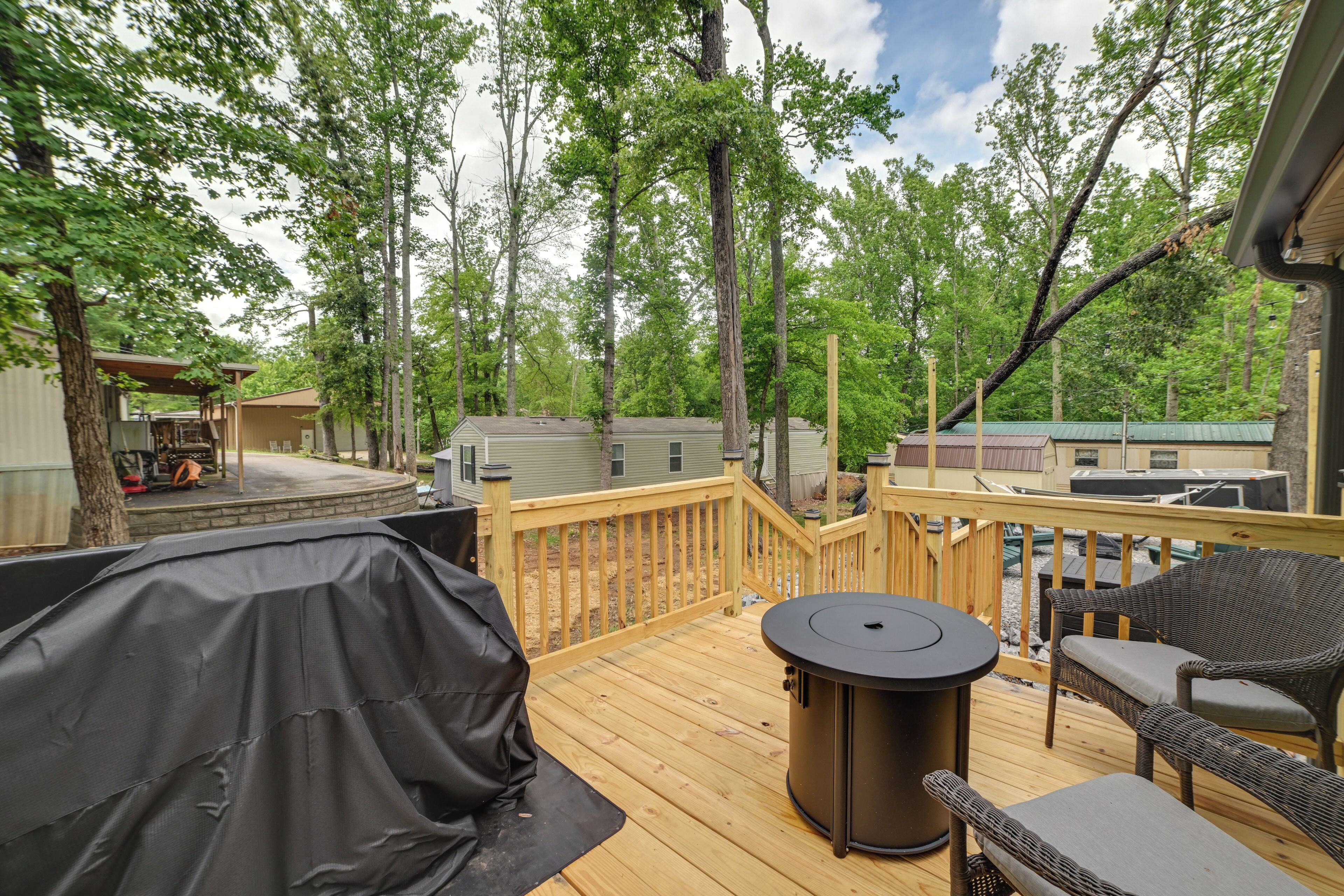 A deck with outdoor furniture, a barbecue grill, and a view of the surrounding wooded area.
