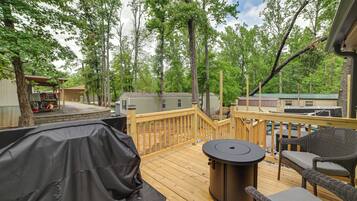 A deck with outdoor furniture, a barbecue grill, and a view of the surrounding wooded area.