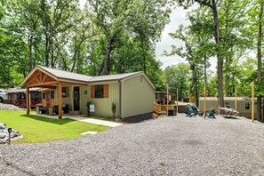 A lodge with a covered porch, a gravel driveway, and a fenced-in area with outdoor seating. - Hot Tub, Deck! Tiny Home Retreat By Kentucky Lake (Springville)