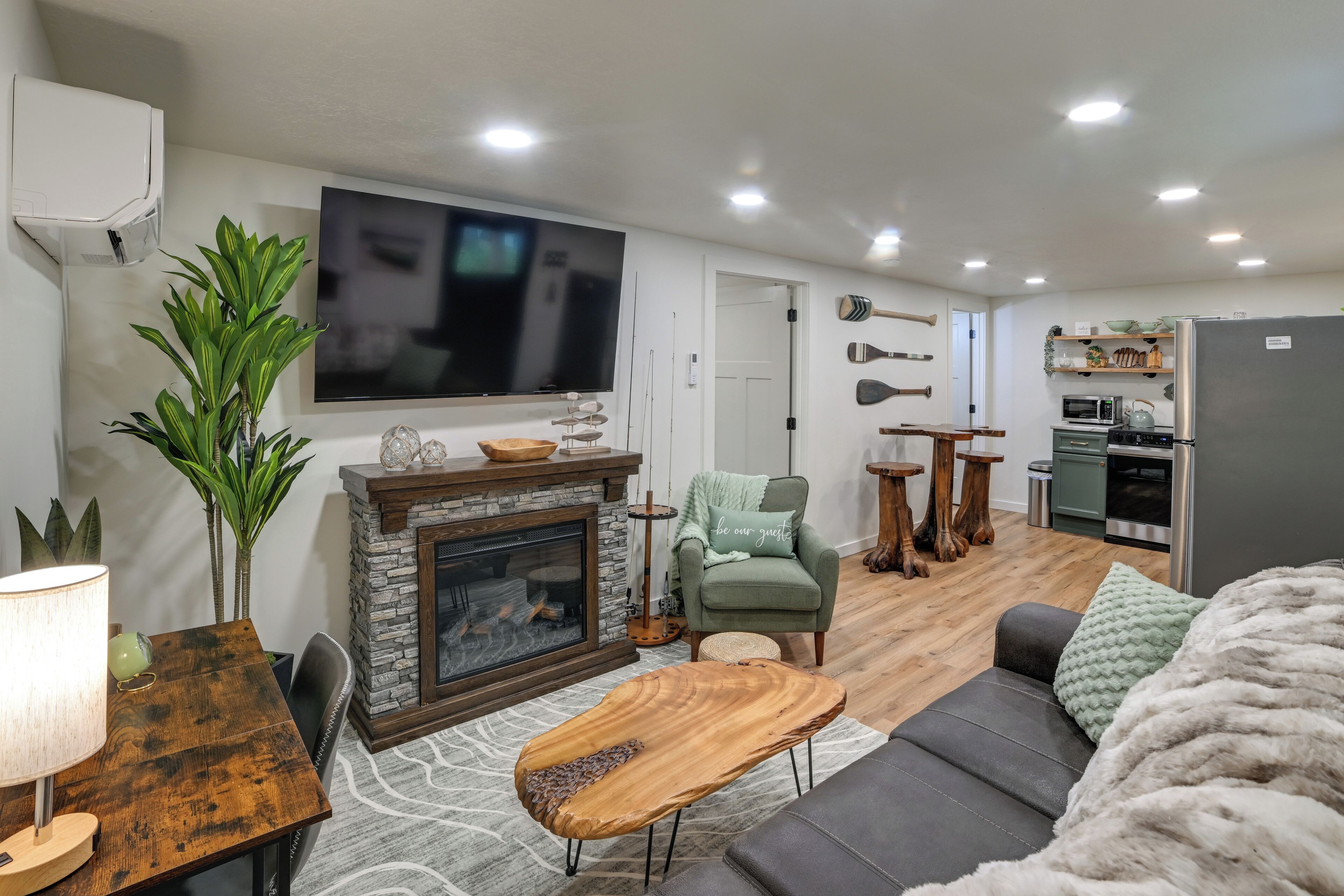 A living room with a fireplace, a TV, a sofa, a dining table, and a kitchen area.
