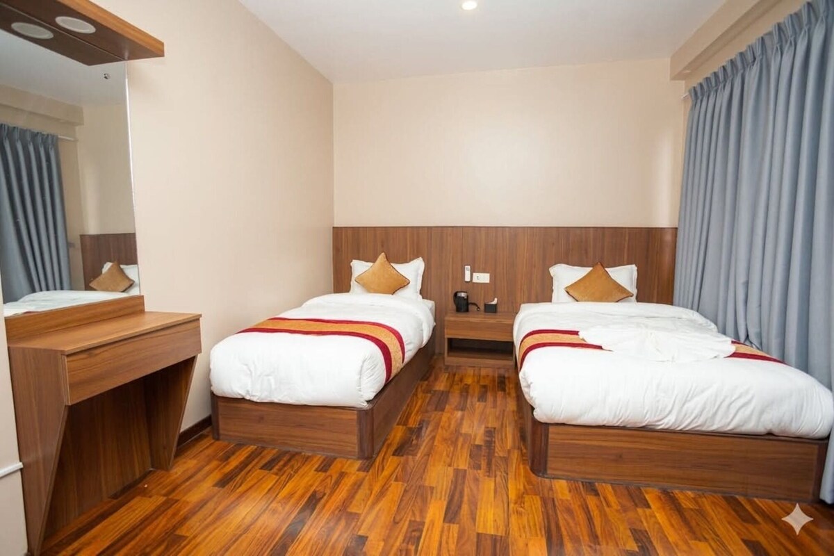 Habitación de hotel con dos camas, cabeceros de madera, un escritorio y un espejo.