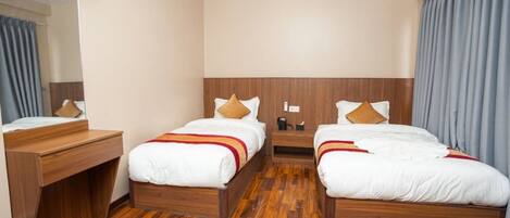 Ein Hotelzimmer mit zwei Betten, Holz-Kopfteilen, einem Schreibtisch und einem Spiegel.
