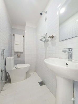 Un baño con inodoro, lavamanos, ducha y espejo.