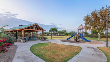 A park with a pavilion, playground, and a clear sky.