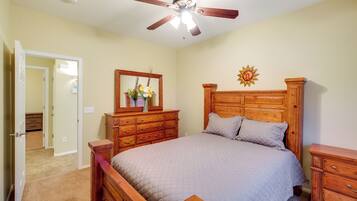 A bedroom with a wooden bed, a ceiling fan, a dresser, and a mirror.