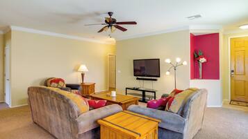 A living room with a ceiling fan, a flat-screen TV, a coffee table, and two sofas.