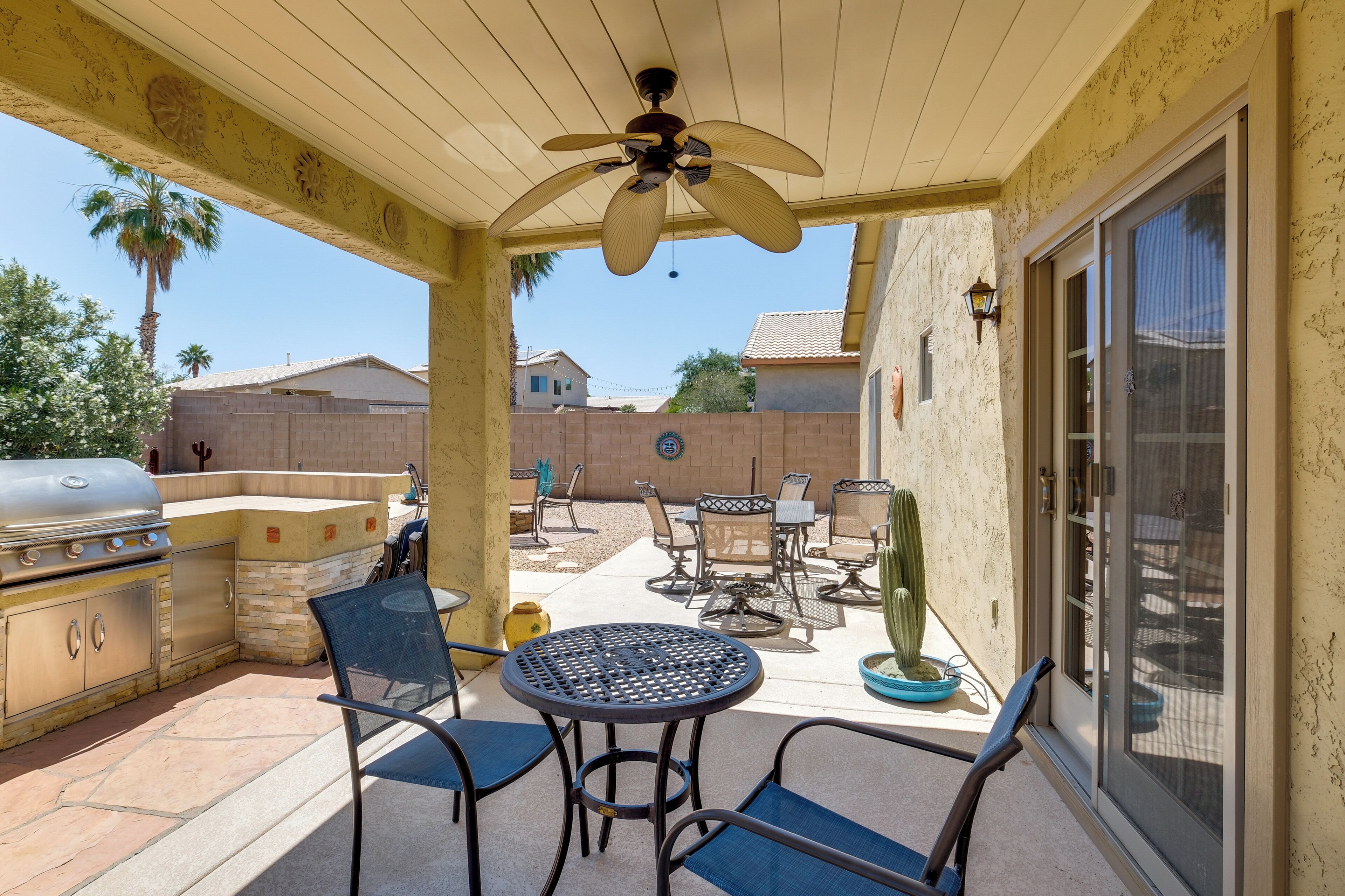 An outdoor patio with a ceiling fan, a grill, and patio furniture.