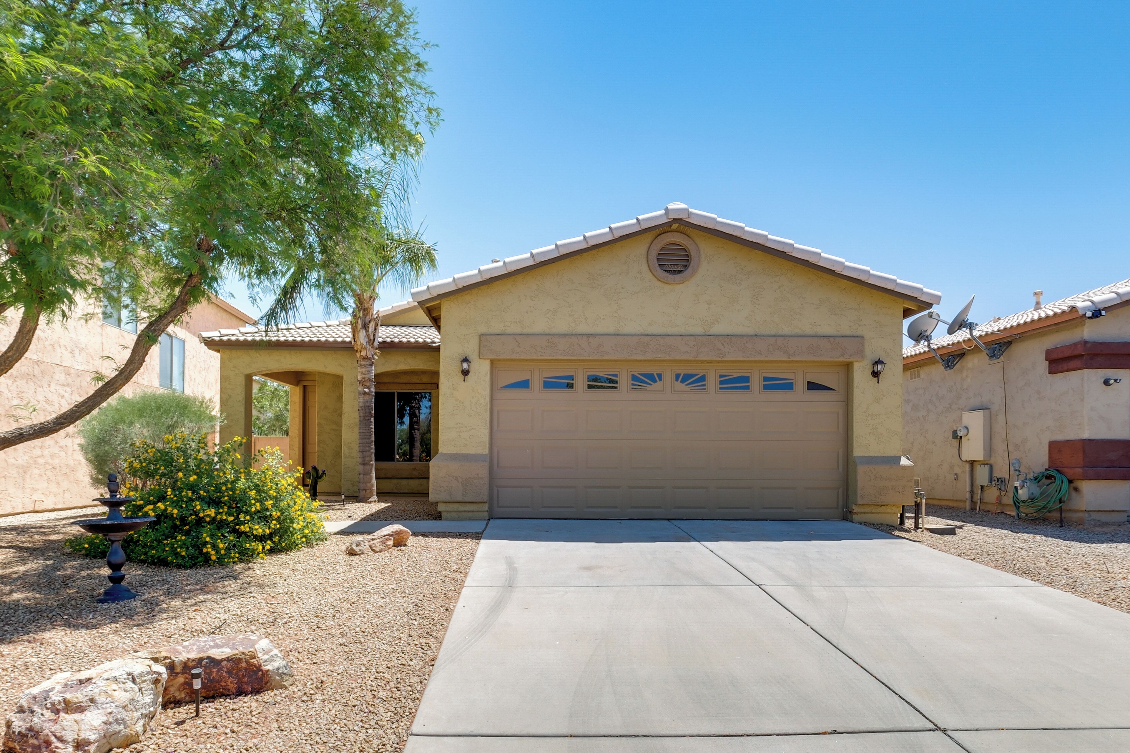 A single-story house with a garage, a patio area, and a small garden with a fountain.