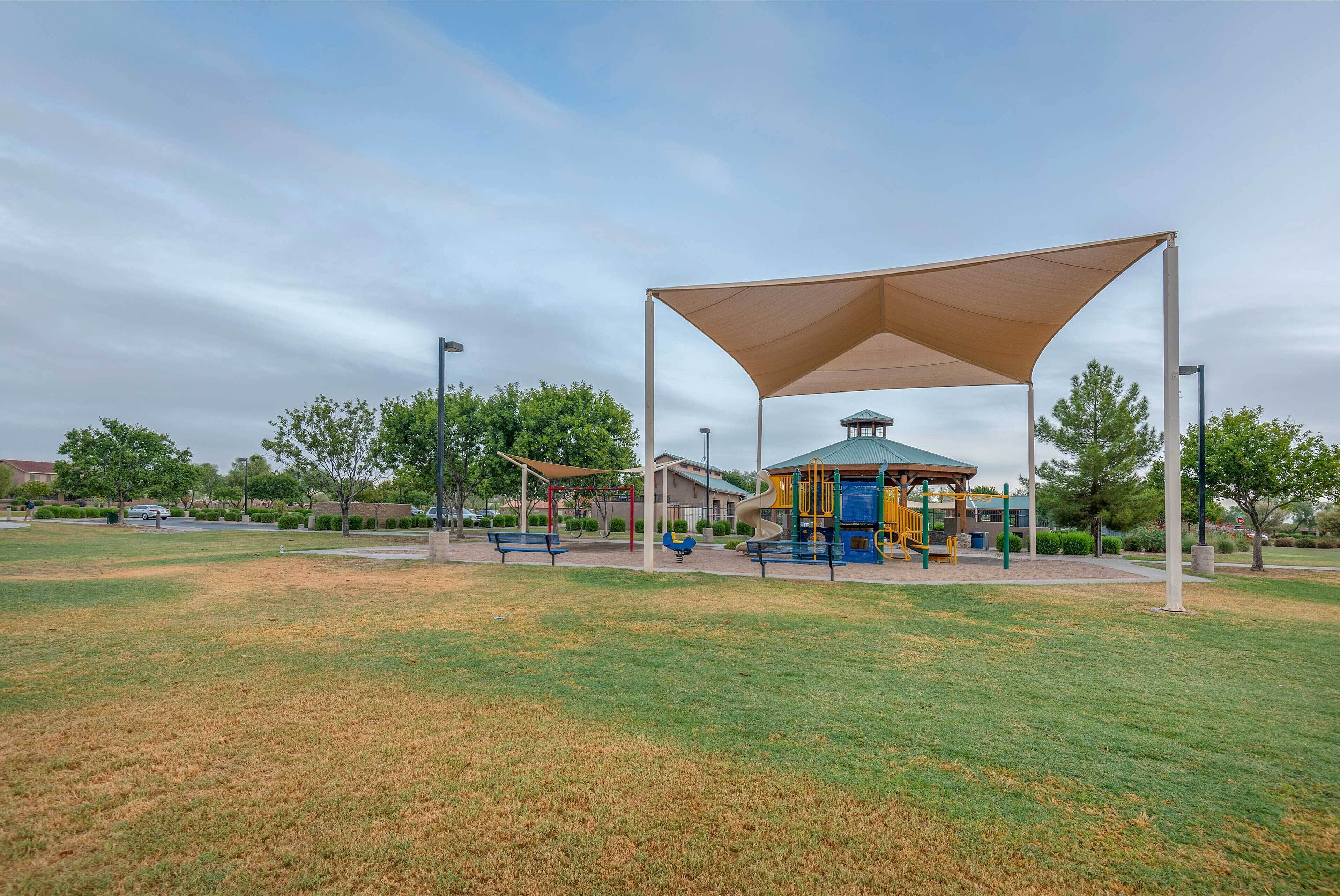 A park with a playground, a covered seating area, and a gazebo.
