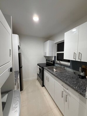 A modern kitchen with white cabinets, a granite countertop, a built-in oven, and a sink. - Modern Miami Home near Wynwood, Downtown & S Beach (Miami)