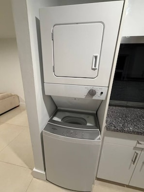 Ein kompakter, moderner Waschraum mit integriertem Wäscheschrank und Trockner, Bedienfeld und einem kleinen Stauraumschrank.