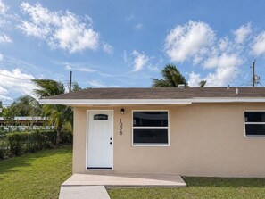 A single-story house with a white door, a small window, and a mailbox.