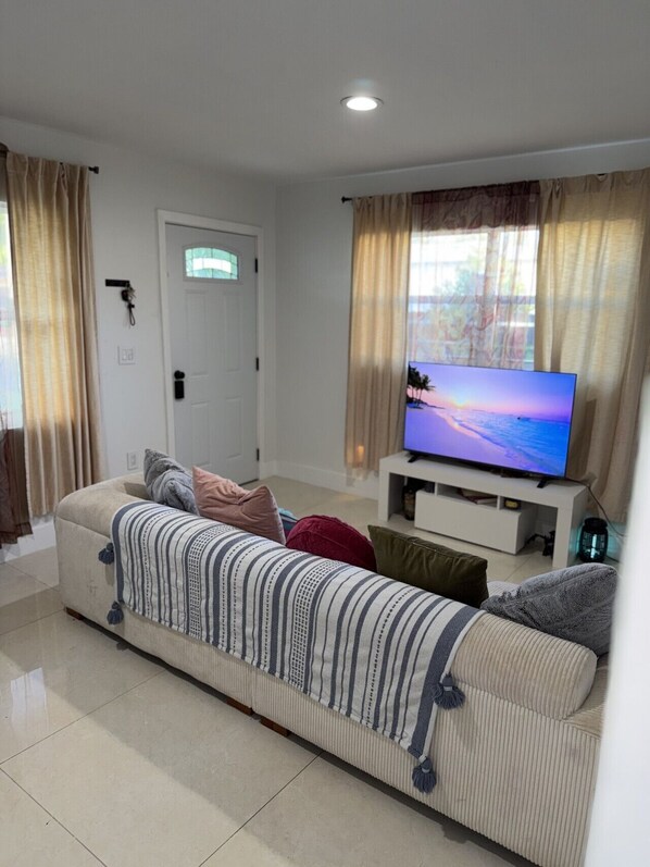 A living room with a sofa, TV, and curtains.