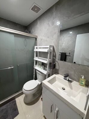 Ein modernes Badezimmer mit Toilette, Waschbecken, Spiegel und Duschbereich.
