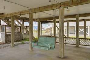 Eine Holterrasse mit einer Schaukel, einem Betonboden und Blick auf Gebäude im Hintergrund.