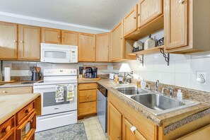 A kitchen with wooden cabinets, a microwave, a stove, a dishwasher, and a granite countertop.
