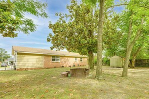 A single-story house with a garage, a small shed, and a tree in the yard.